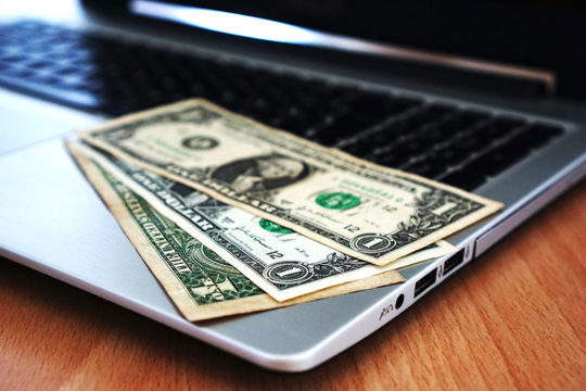 Kompjuter laptop dhe dollarë mbi tastierë