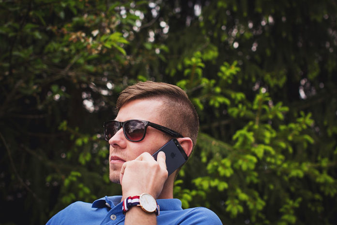 Një djalë me syze që flet në telefon