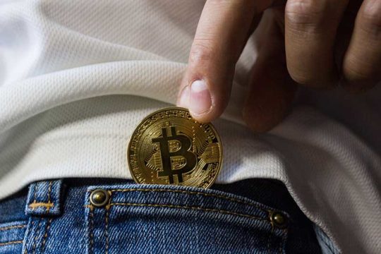 Nje dore duke futur nje kriptomonedhe bitcoin ne xhepin e pantallonave