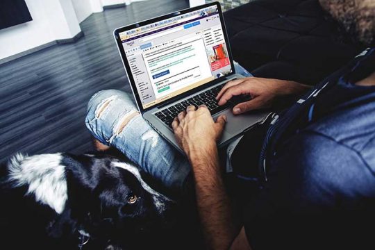 Djale me hinse me je kompjuter laptop mbi gju duke shkruar ne facebook